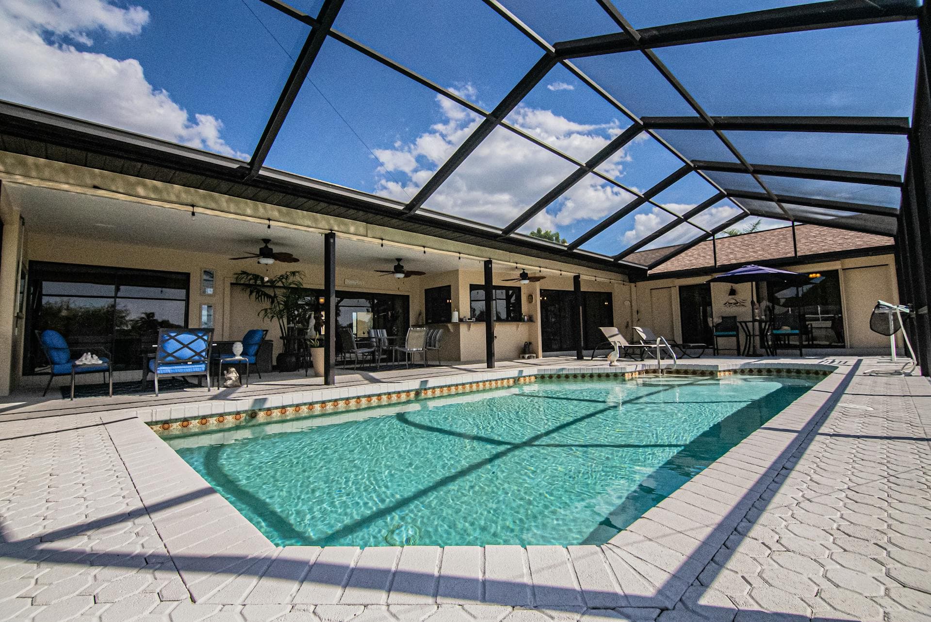 Luxury senior living community outdoor pool area with covered seating and blue skies.