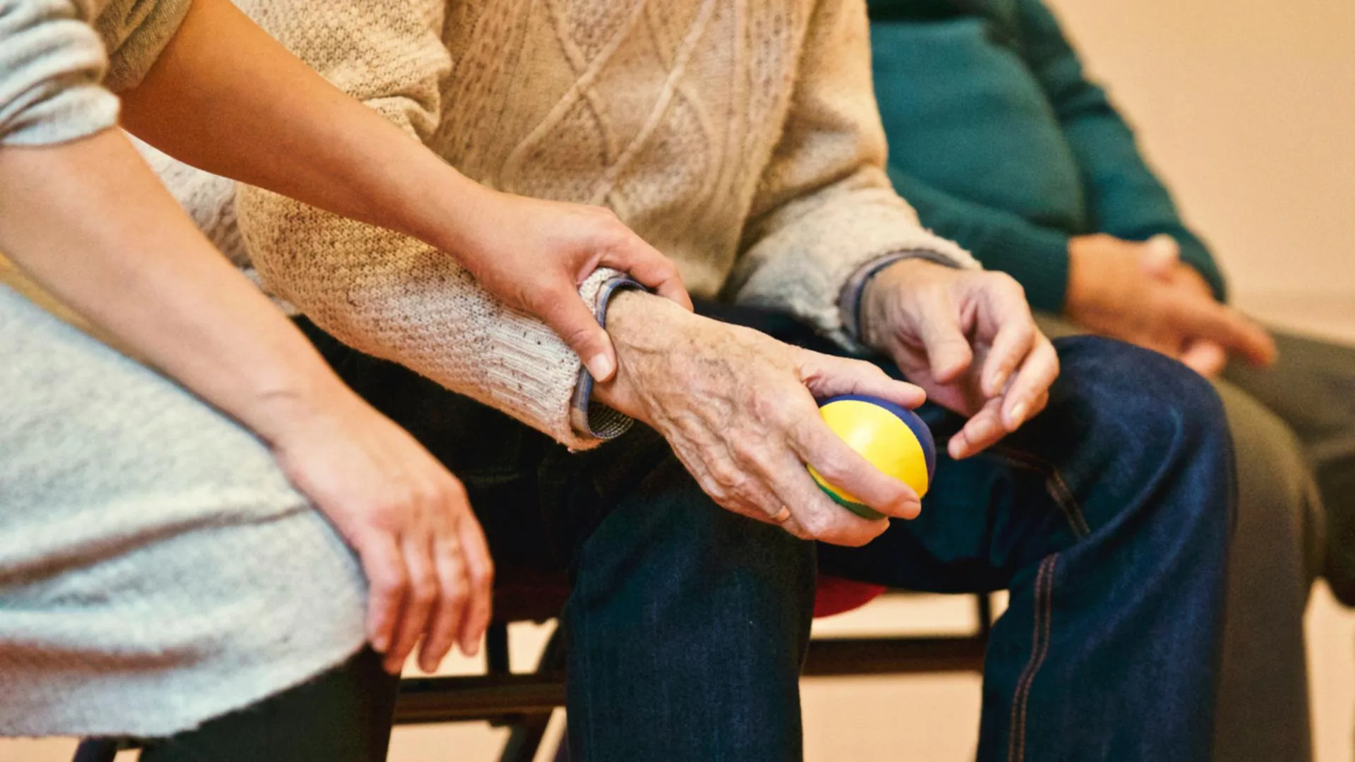 Caregiver assisting an elderly person with a therapy ball.