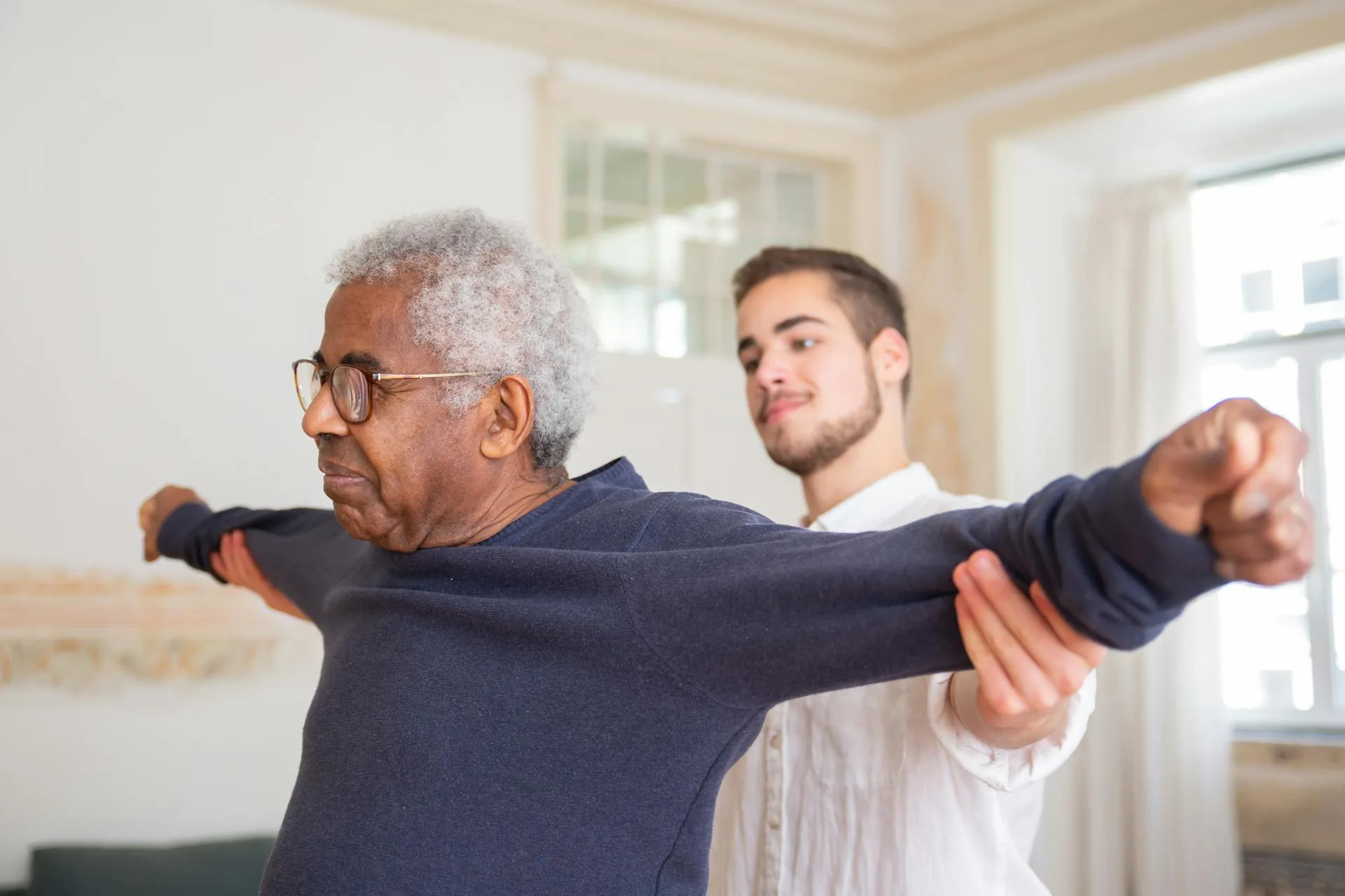 Senior man receiving physical therapy assistance from a caregiver.