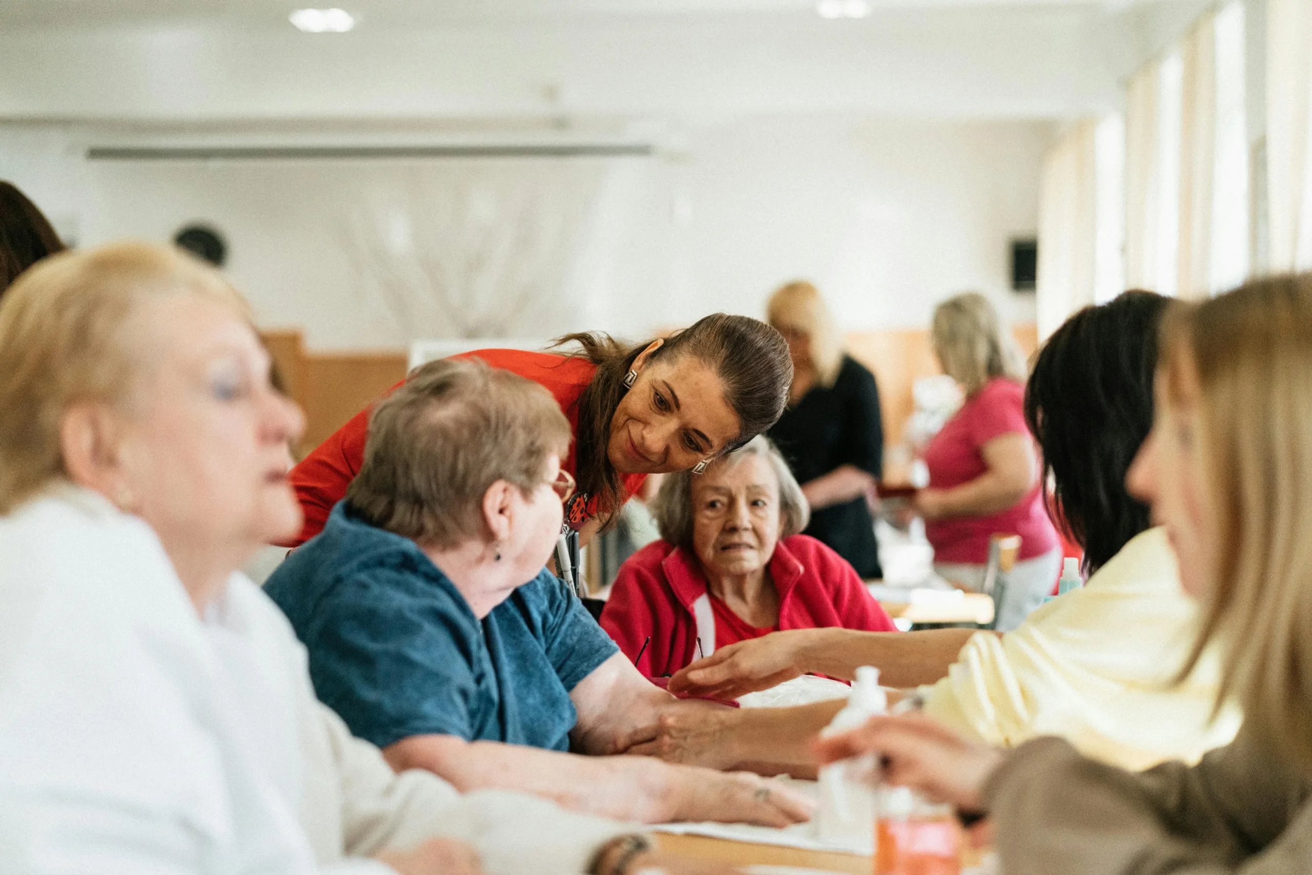 Caregiver interacting with elderly residents during a group activity.